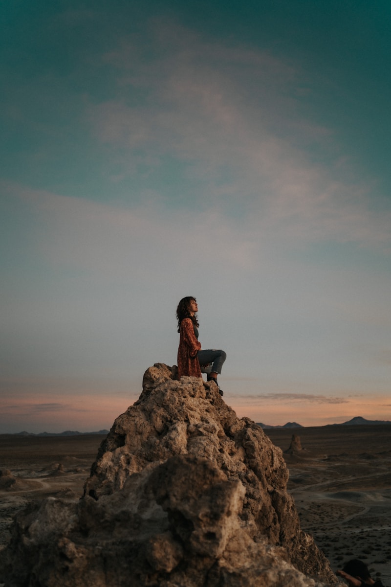 A person sitting on top of a large rock